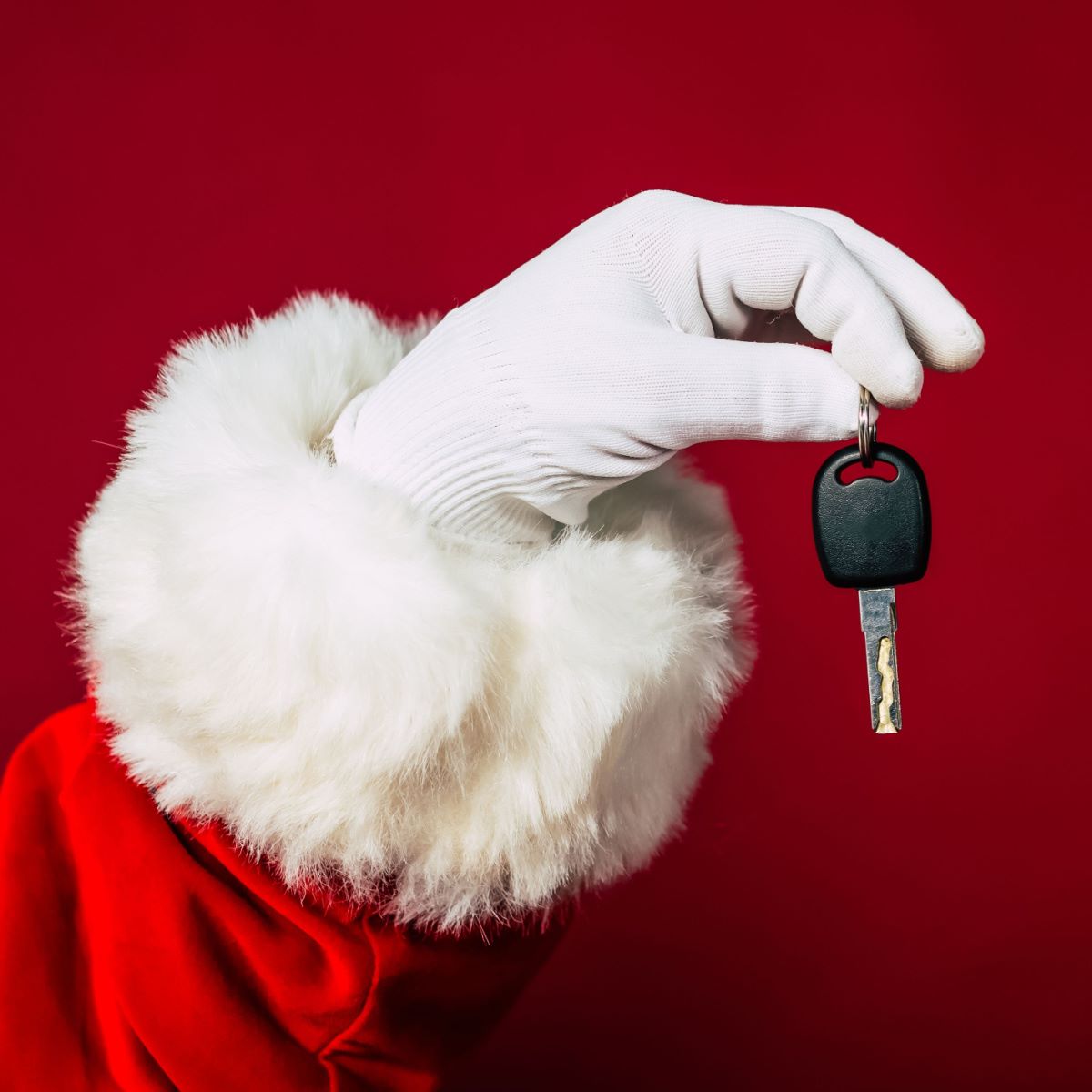 Close up of Santa's hand holding a car key, reminding everyone to drive safely this holiday season.